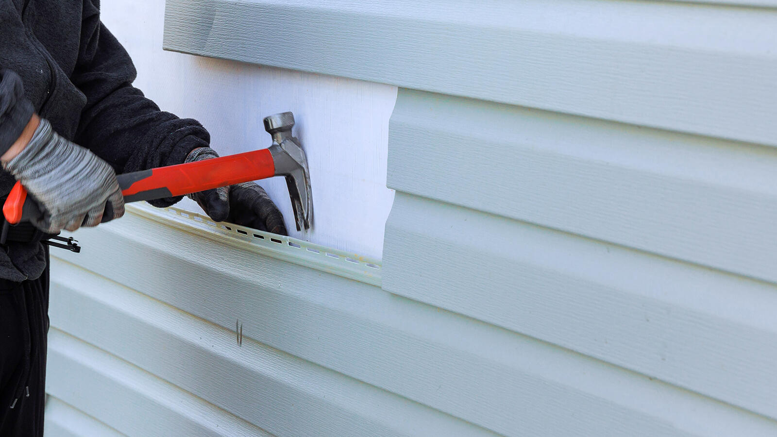 Close-up of a shingled roof with a background of house rooftops and sky.